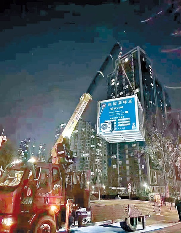 北京市街頭有吊車吊起核酸檢測亭。