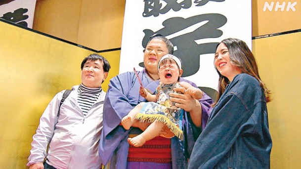 冠軍相撲手宇良抱着比賽總冠軍寶寶拍照。