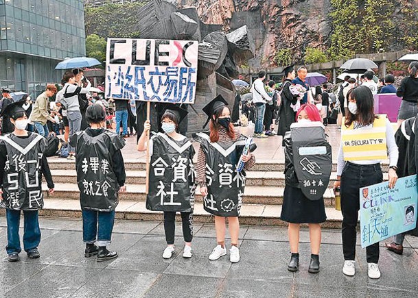 多名學生身穿貼有諷刺性字眼的「畢業袍」，在中大「烽火台」前抗議。