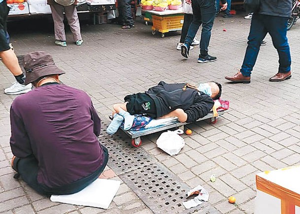 元朗：元朗街頭重現內地「丐幫」二人組，一男子盤坐，肌肉萎縮男子躺板車行乞。（受訪者提供）
