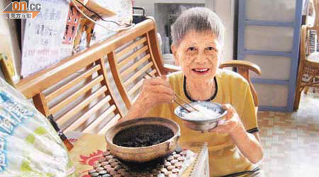 譚婆婆將獲贈白米煮成熟飯後，進食時不禁流露滿足笑容。