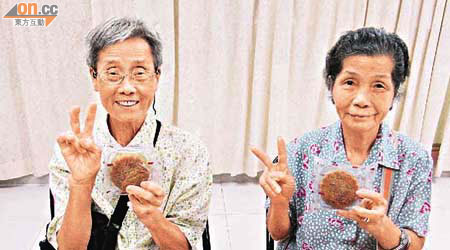 梁應琼婆婆（左）獲贈月餅後樂不可支。戚仲好婆婆（右）亦不忘拿起月餅讚好。
