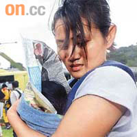 甲仙鄉一名母親用報紙包住嬰兒，準備搭乘直升機到安全地點。	（本報高雄傳真）