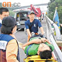 救援人員從旅遊巴士車底救出被困傷者。	（本報高雄傳真）
