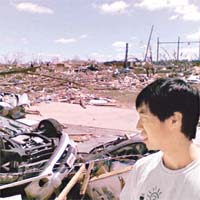 一名大學生無奈地看着被毀壞的家園。（中新社圖片）