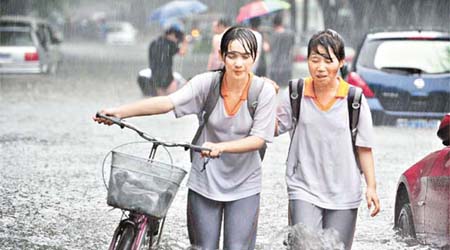 北京暴雨下，西城百萬莊南街水深過膝，路人狼狽。	（中新社圖片）