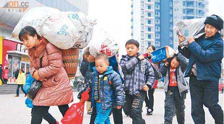 一個民工家庭提着行李到重慶火車站踏上返城之路。（中新社圖片）