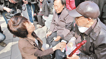 松岡環（左）單膝跪地，慰問南京大屠殺的幸存者。（中新社圖片）