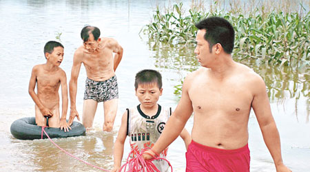 廣西桂林的救援人員，將被河水圍困的小童救上岸。（中新社圖片）