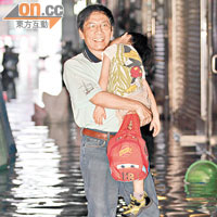 高雄市鼓山地區水浸，一名父親抱着兒子前行。（郭良傑攝）