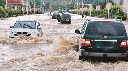 遼寧蓋州市嚴重水浸，車輛在積水中前行。（中新社圖片）