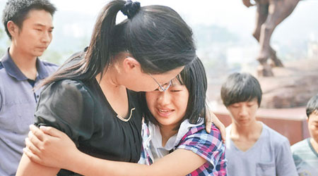 彝良縣學生擁着地震時照顧她的老師，忍不住痛哭。（中新社圖片）