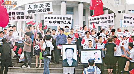 深圳有大批商戶在法院外抗議，侯姓男子手捧自殺父親的遺照在現場致哀。（本報深圳傳真）