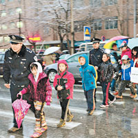 瀋陽民警冒雪護送小學生過馬路。（中新社圖片）