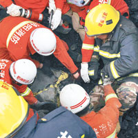多名消防員徒手從廢墟挖掘遇難者。（中新社圖片）
