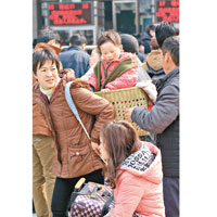 湖北武漢武昌火車站返程旅客用背簍揹起小童等待入站。（中新社圖片）