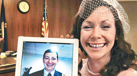美國多州僅批准軍人網婚。圖為去年空軍成員費爾普斯（螢幕中）與其妻卡里舉行網婚。（資料圖片）