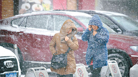 烏魯木齊降雪，民眾外出身穿厚衣。（中新社圖片）