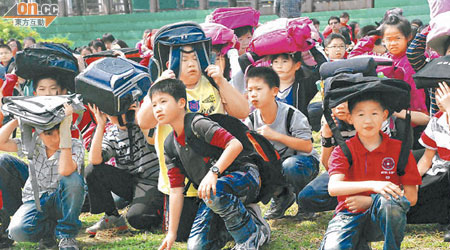 小學生攜帶書包疏散到操場。（本報南投傳真）