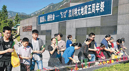 汶川映秀鎮漩口中學遺址舉行紀念活動，民眾於公墓前祭奠死難者。　（中新社圖片）