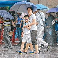 手持雨傘的民眾亦要到北京站前避冰雹。（中新社圖片）