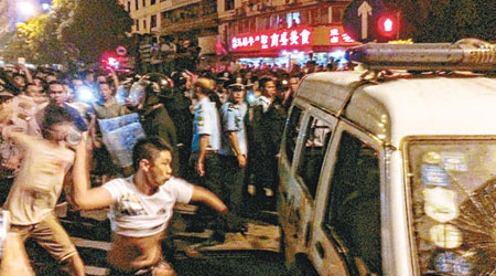 憤怒的民眾向警車投擲物件洩憤。（中新社圖片）