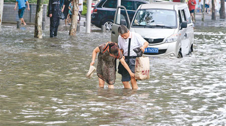 武漢街頭水深及膝，民眾涉水而行。（中新社圖片）