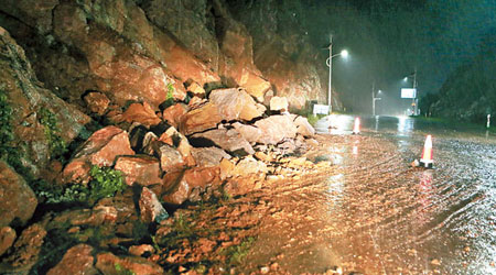 湖南臨武縣一省道發生山泥傾瀉，有大石滾到路邊。（中新社圖片）