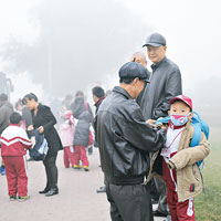 長春有戴口罩的小學生在街邊等校車。（中新社圖片）