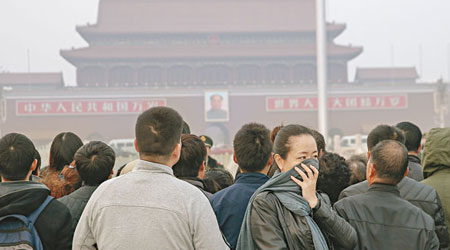 北京<br>內地多個省市連日遭霧霾天氣襲擊。圖為一名女子在北京天安門廣場用圍巾捂鼻。（中新社圖片）