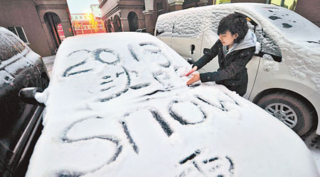 行人在車輛積雪上塗鴉。（中新社圖片）