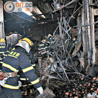 救援人員在被燒至焦黑的鐵皮屋搜救。