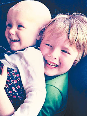 布雷默接受化療後頭髮掉光，哥哥抱着她玩耍。（互聯網圖片）