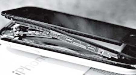 汪先生的iPhone 3GS被炸至外殼裂開，主板彎曲變形。（互聯網黑白圖片）