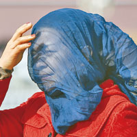 天安門廣場一遊客用紗巾包頭防沙塵。（中新社圖片）