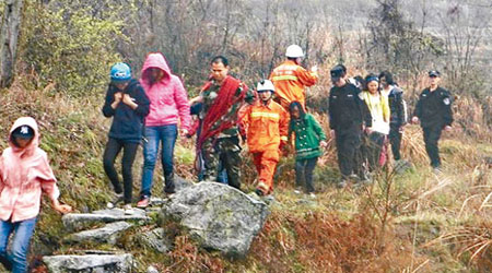 被困的十九名男女大學生，由救援人員攙扶下山。（互聯網圖片）