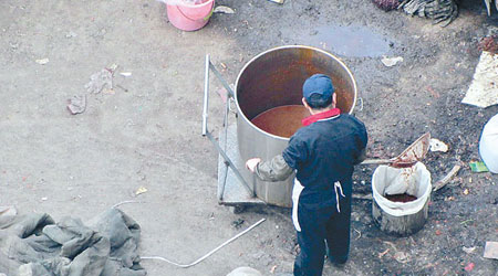 網傳一名廚師在桶中撈出辣椒渣，放到另一個桶中。（互聯網圖片）
