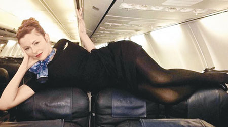 一名空姐躺臥在機艙座椅上，擺出性感甫士。（互聯網圖片）