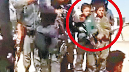 ISIL日前處決大批伊軍及什葉派信徒，照片可見有小孩持槍（紅圈示）在場參與。（互聯網圖片）