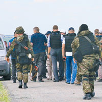 歐洲安全合作組織成員在武裝分子監視下離開墜機現場。（互聯網圖片）
