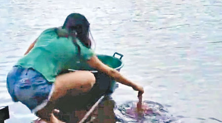 巴西一名少女把誘餌放進水中。（互聯網圖片）