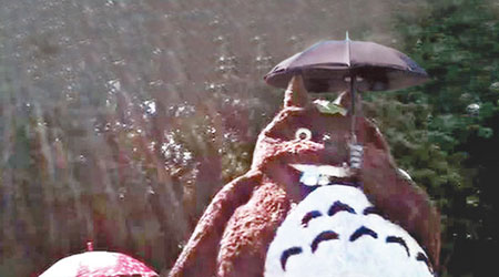 日翁的的兩名孫女站在大龍貓旁，擔着傘子拍照。（互聯網圖片）