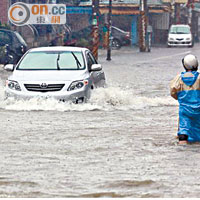 高雄多處嚴重水浸，車輛行人均強行而過。（郭良傑攝）