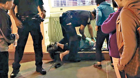 其中一名華裔婦人被警員壓在地上，鎖上手銬。（互聯網圖片）