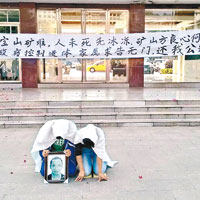 死者家屬在涉事企業門外拉起橫額下跪抗議。（互聯網圖片）