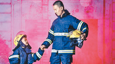小煜銘身穿迷你消防服，與消防員合照，堪稱「萌爆」。（互聯網圖片）
