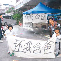 戴姓死者的母親及兩名年幼子女在街頭拉橫額抗議。（互聯網圖片）