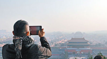 北京<br>一名遊客趁前日霧霾稍散，在北京景山公園俯拍故宮。（中新社圖片）