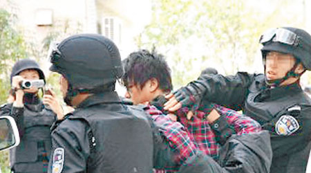 覃男被警方制服後，押上警車。（互聯網圖片）