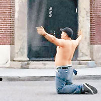 男子赤裸上身向天開槍，跪在馬路中心，張開雙手。（互聯網圖片）